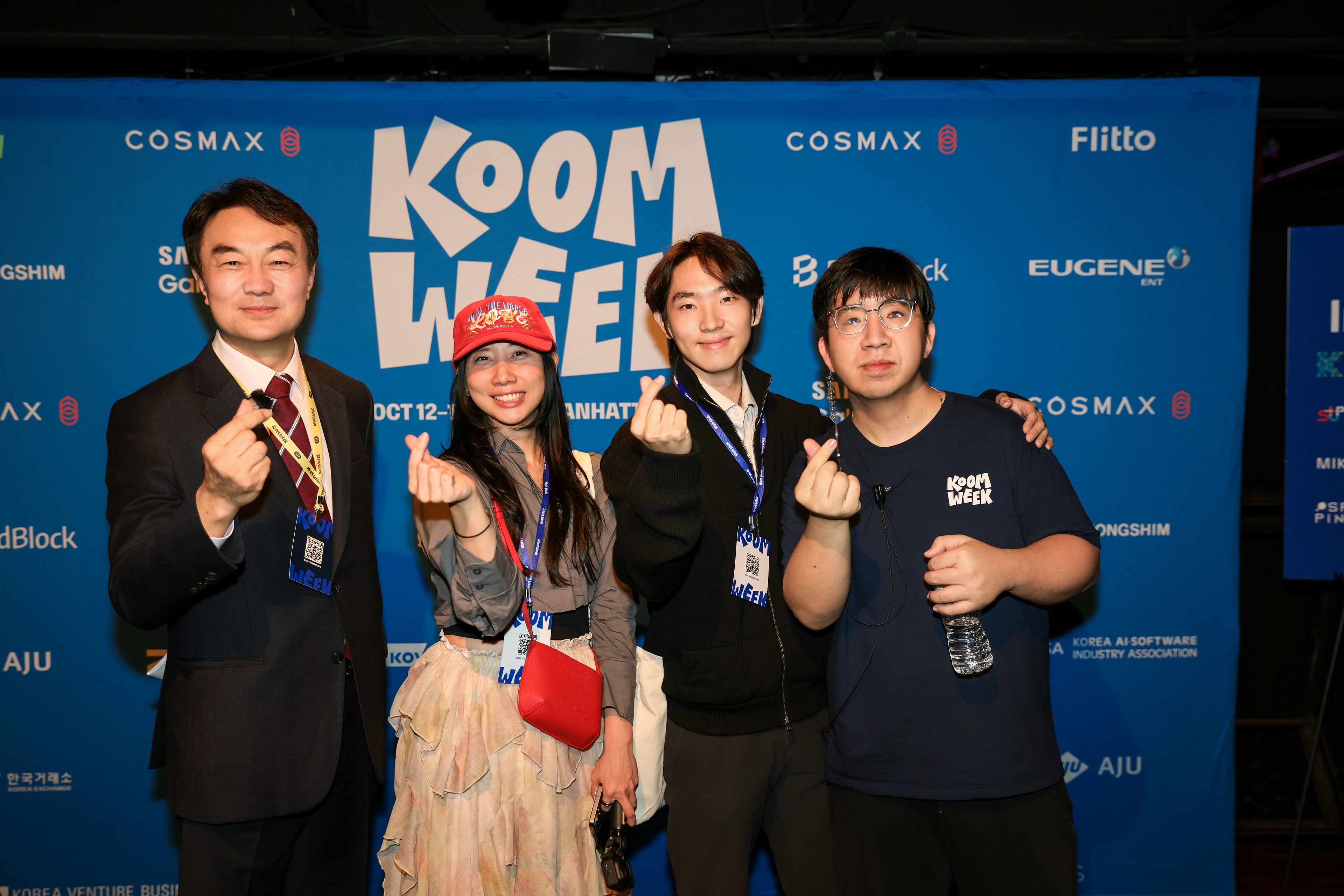 Attendees posing at the KOOM Week backdrop